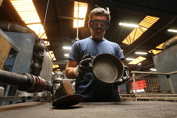 worker make le crueset cookware in a factory