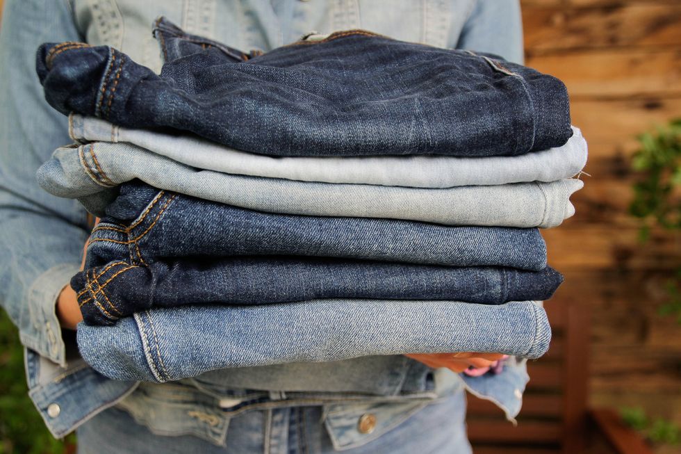woman holding stack of denim